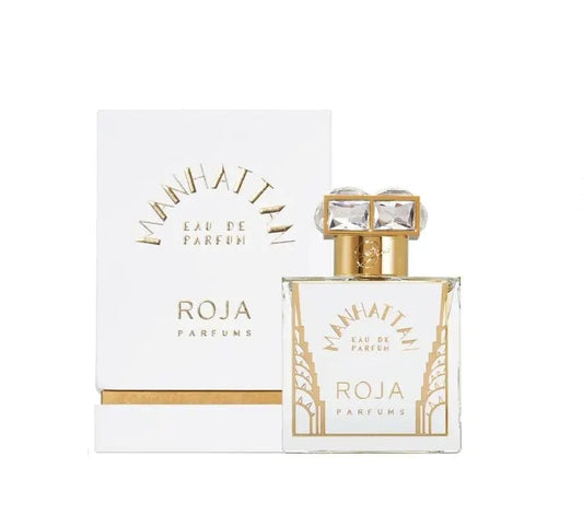 The Roja Parfums Manhattan perfume bottle, with its sleek, faceted design and elegant gold and diamond cap, displayed alongside its prestigious white and gold box. The image emphasizes the luxurious and high-end presentation of the product.